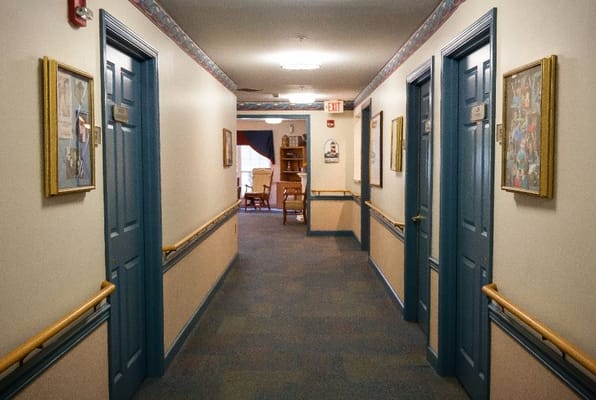 A hallway with resident room doors and artwork