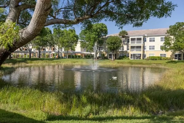 Scenic pond with fountain in front of a senior living facility