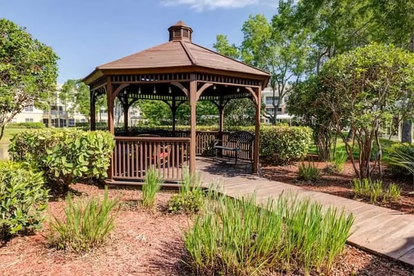 A wooden gazebo in a landscaped garden