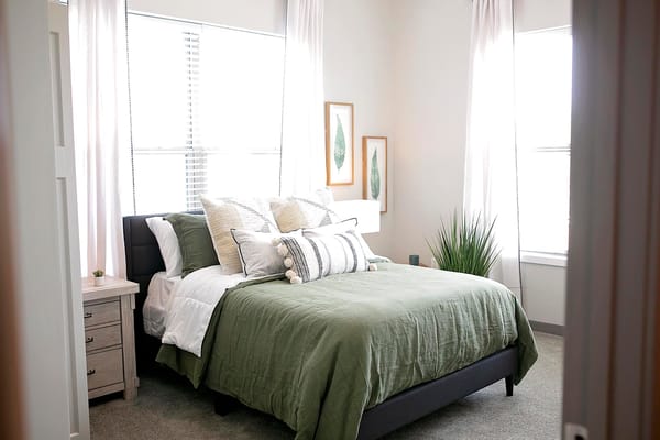 Cozy bedroom with a green comforter and natural light