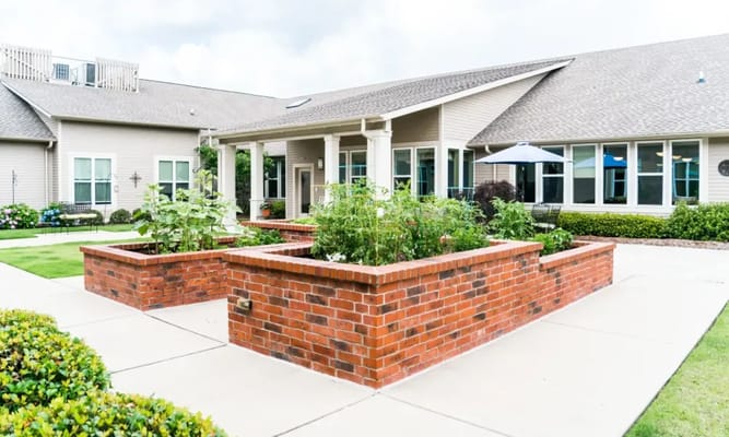 Courtyard with flower beds and seating area at Avenir Memory Care
