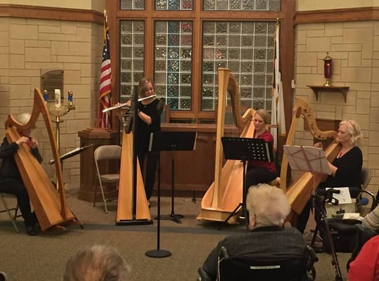 Residents enjoying a harp concert in a common area