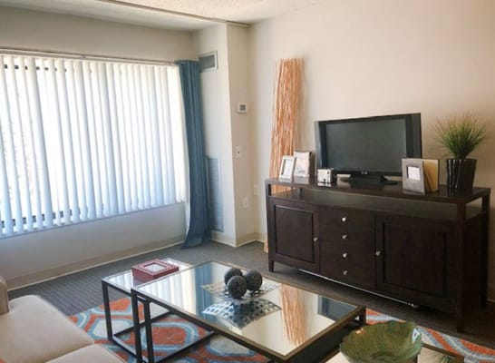 Cozy living room with a television, coffee table, and window blinds
