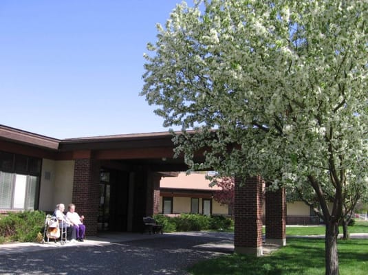 Two residents sitting outside under a flowering tree
