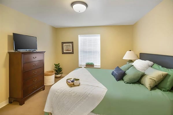 Well-decorated private resident room with a bed and TV