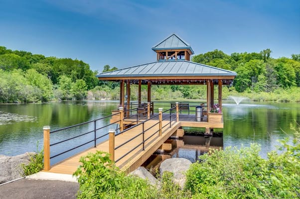 Wooden pavilion with a roof beside a tranquil lake