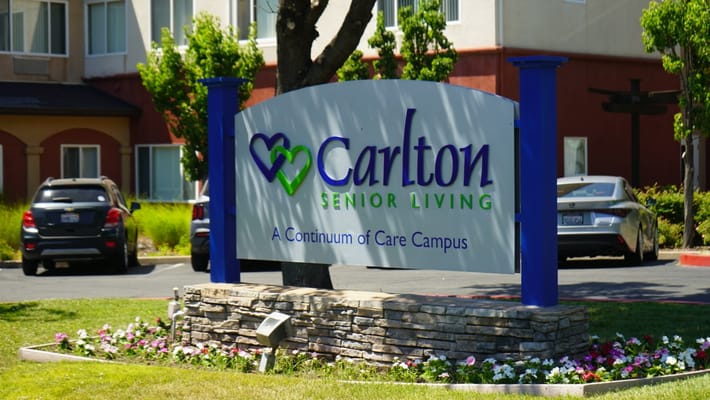Sign for Carlton Senior Living with landscaped garden