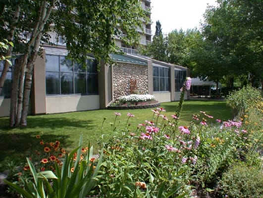 Exterior view of a senior living facility with flowers and lawn