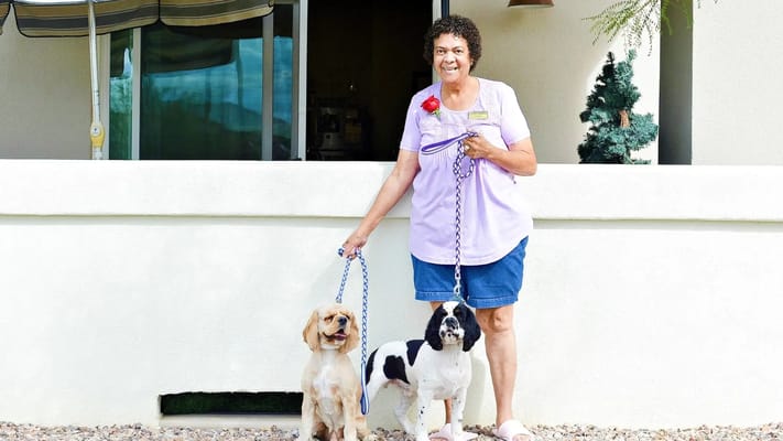 A female resident holding leashes of two dogs outside the community.