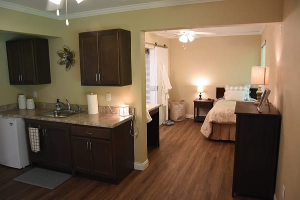 A kitchen area adjacent to a bedroom in a senior living facility.