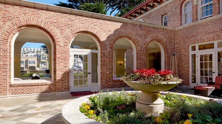 Beautiful courtyard with a flower fountain surrounded by brick archways.