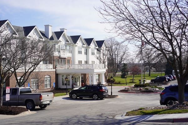 Exterior view of a senior living facility with cars parked