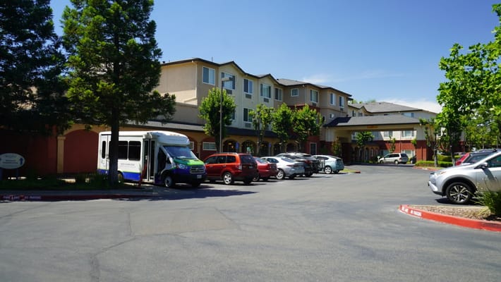 Exterior view of a senior living facility with parked vehicles