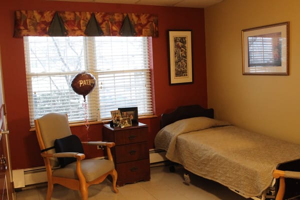 A cozy resident room with a bed and chair