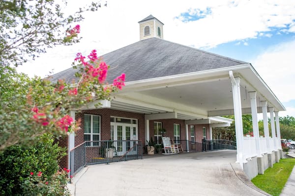 Exterior view of the entrance to Dunbar Village Terrace with pink flowers in the foreground.