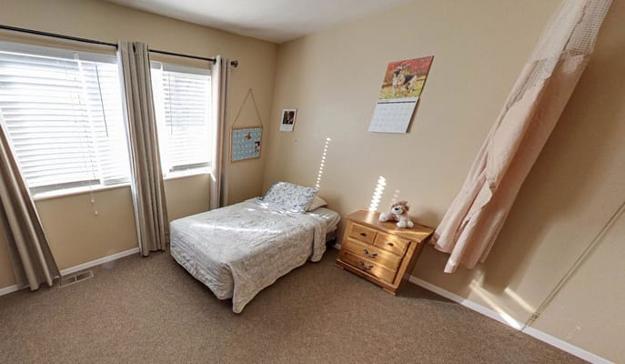 Cozy bedroom featuring a twin bed, wooden dresser, and natural light.