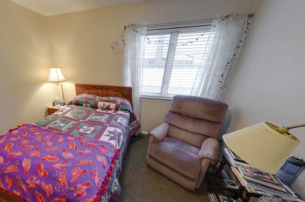 A cozy bedroom featuring a bed with colorful blankets and a comfortable chair.