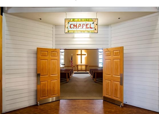 Entrance to the chapel with wooden doors and stained glass sign