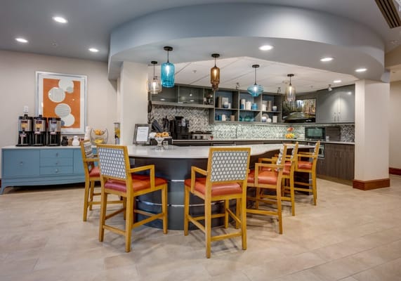 A bright common area with a stylish kitchen bar and seating
