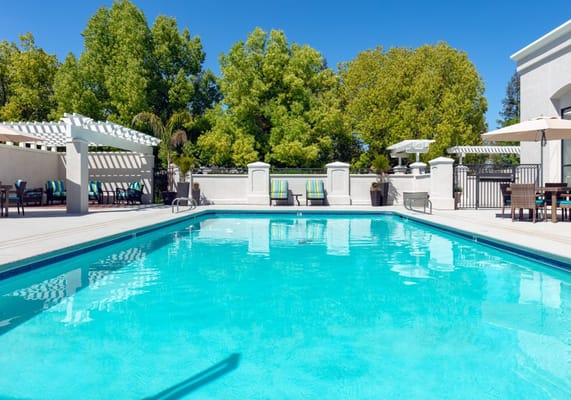 Swimming pool area with lounge chairs under a blue sky