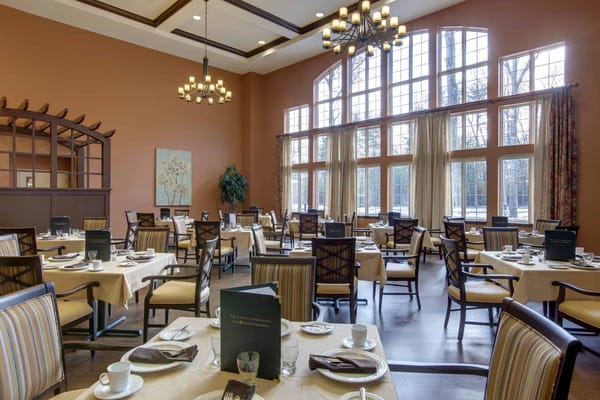 Well-lit dining area with tables set for meals and large windows.