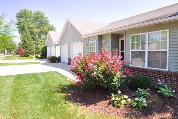 Exterior view showing a flower garden and nearby residences.