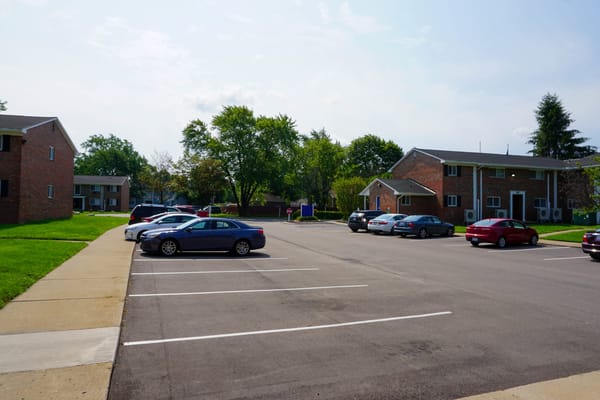 Parking lot with several cars and residential buildings in the background.