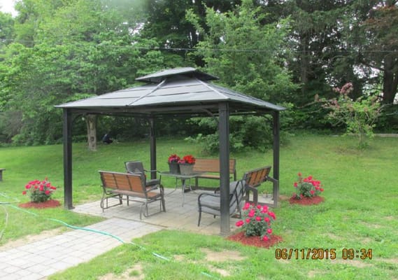 Gazebo with seating and flowers in a garden