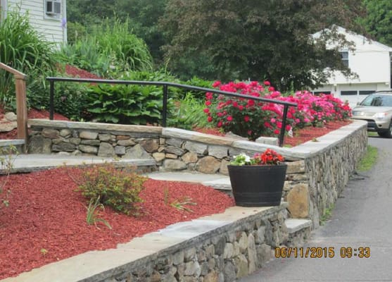Colorful flower beds with stone path and railing