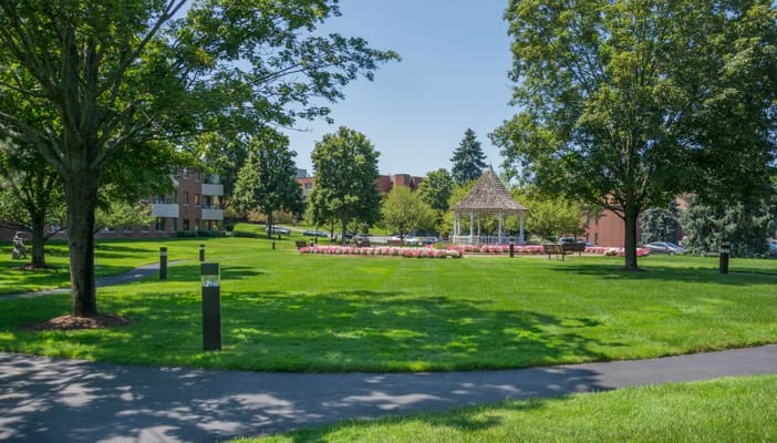 Lush green lawn with gazebo and flower beds at Hampton Suites