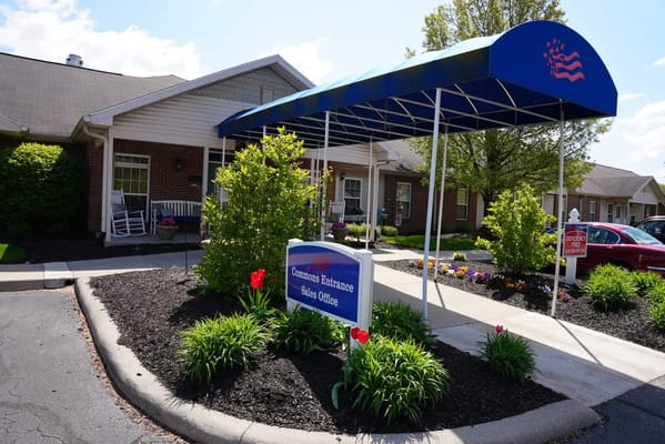 Front entrance with a blue awning and signage at Heritage Park Assisted Living.