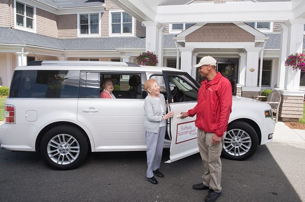 Resident interacting with staff by the facility transport van