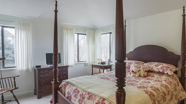 Brightly lit private resident room with a bed and windows