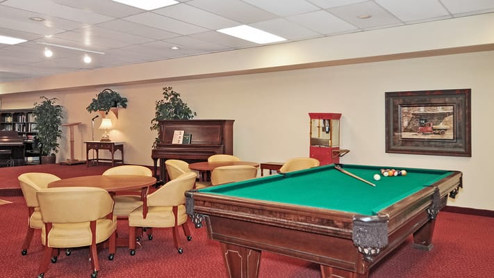 A game room featuring a pool table, seating areas, and a piano.