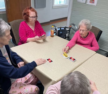 Seniors playing cards at a table in a common area.