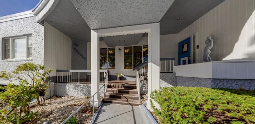 Entrance of a senior living facility with outdoor steps and greenery