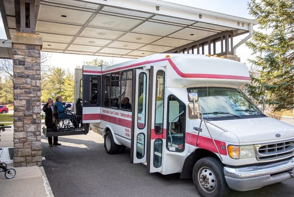 Facility shuttle bus picking up residents at entrance