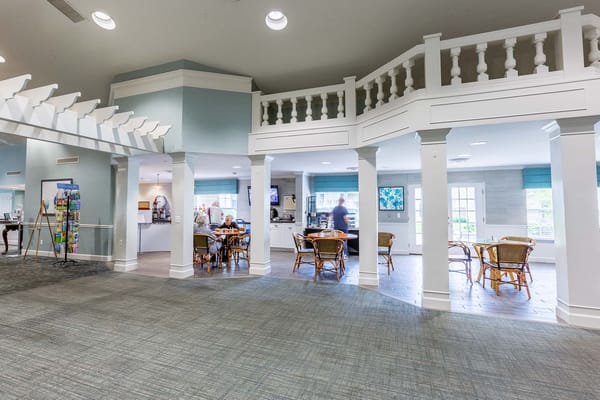 Bright, welcoming common area with dining tables and residents at Independence Village of Brighton Valley.