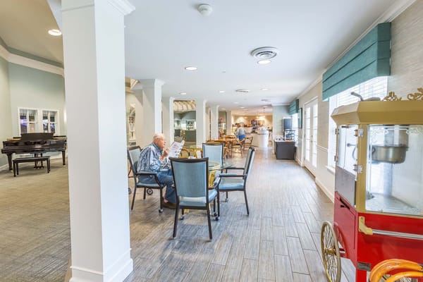 Residents enjoying the common area with a piano and café setup