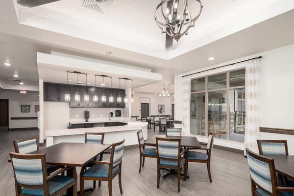 Bright and spacious common area with tables and a kitchenette.