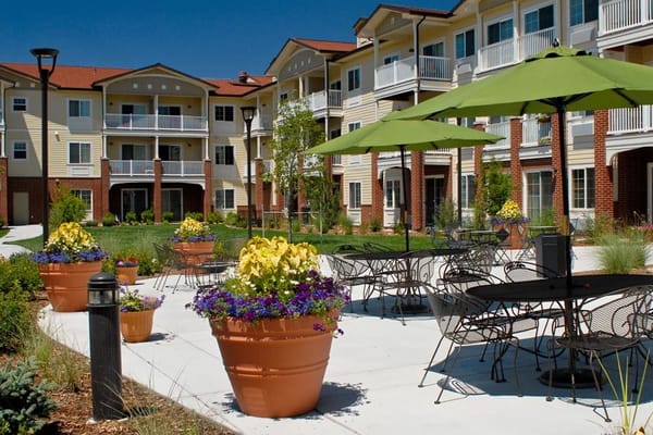Beautiful courtyard with potted flowers and tables under green umbrellas.