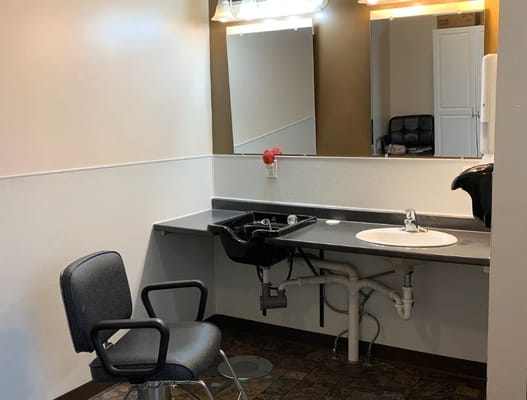 Hair salon station with a chair, sink, and mirror.