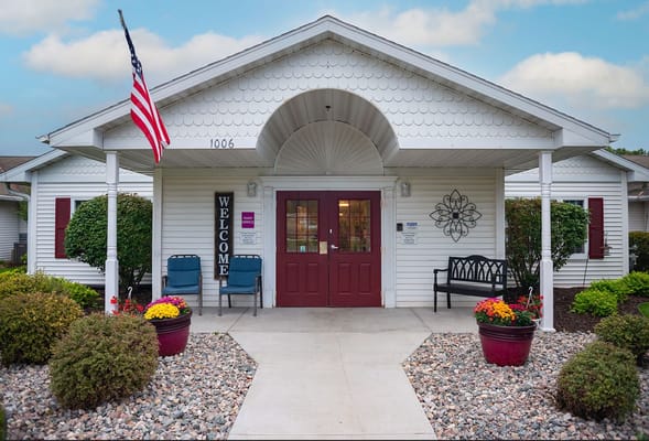 Welcoming entrance with a red door and benches, surrounded by colorful flowers.