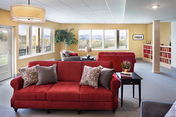 Comfortable red sofas in a well-lit living room with large windows.