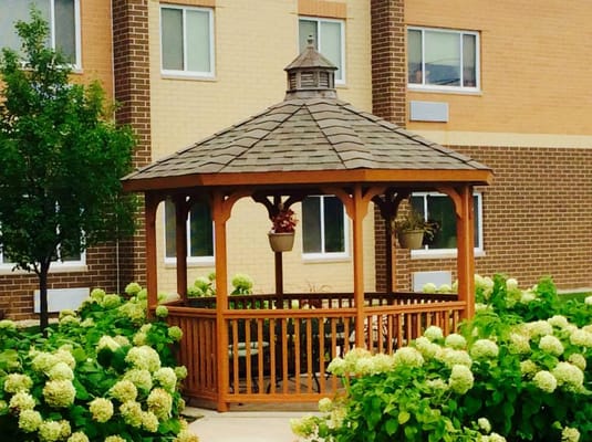 A gazebo surrounded by blooming hydrangeas in an outdoor space.