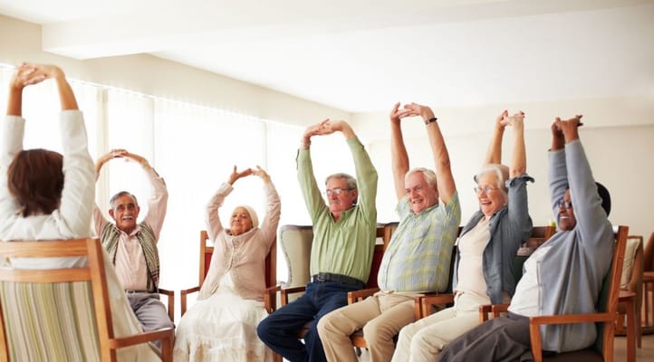Group of seniors participating in a stretching exercise session in a community room.