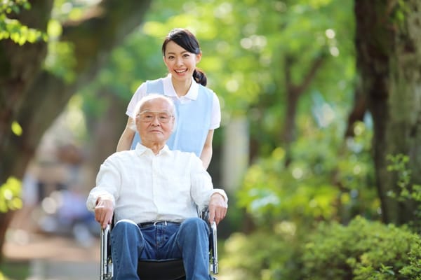 Caregiver pushing a resident in a wheelchair in a garden