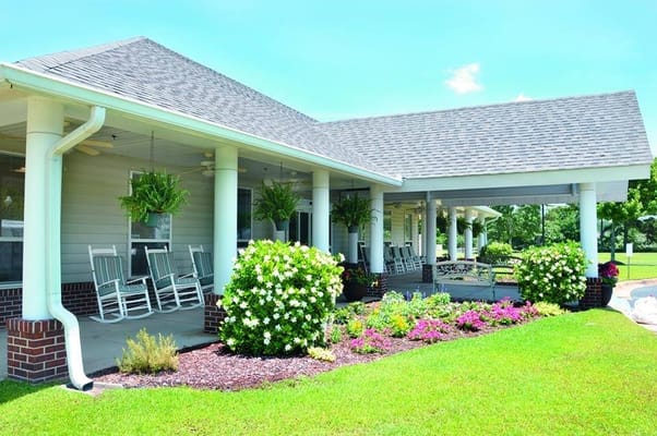 Exterior view of North River Village with rocking chairs and flowers
