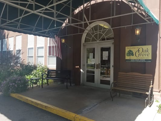Entrance of Oak Grove Assisted Living with seating area and flowers