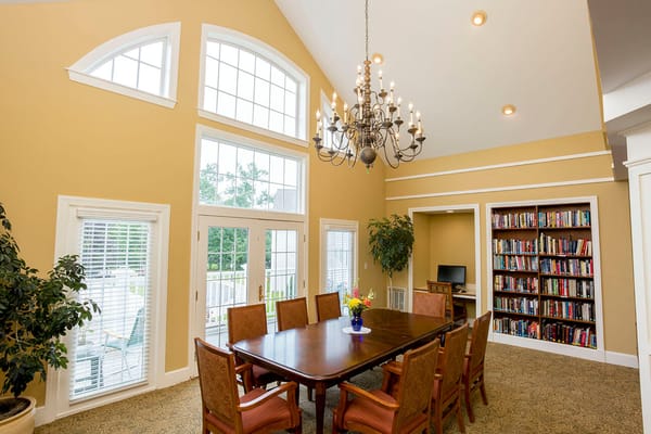 Bright dining area with large windows and a chandelier.